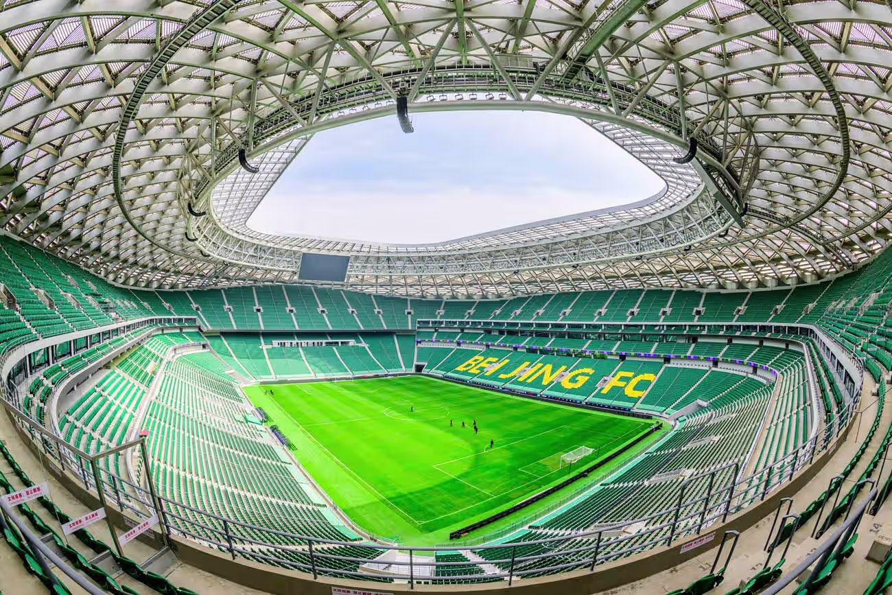 Beijing FC stadium with green seats and BIPV solar panels on the roof.