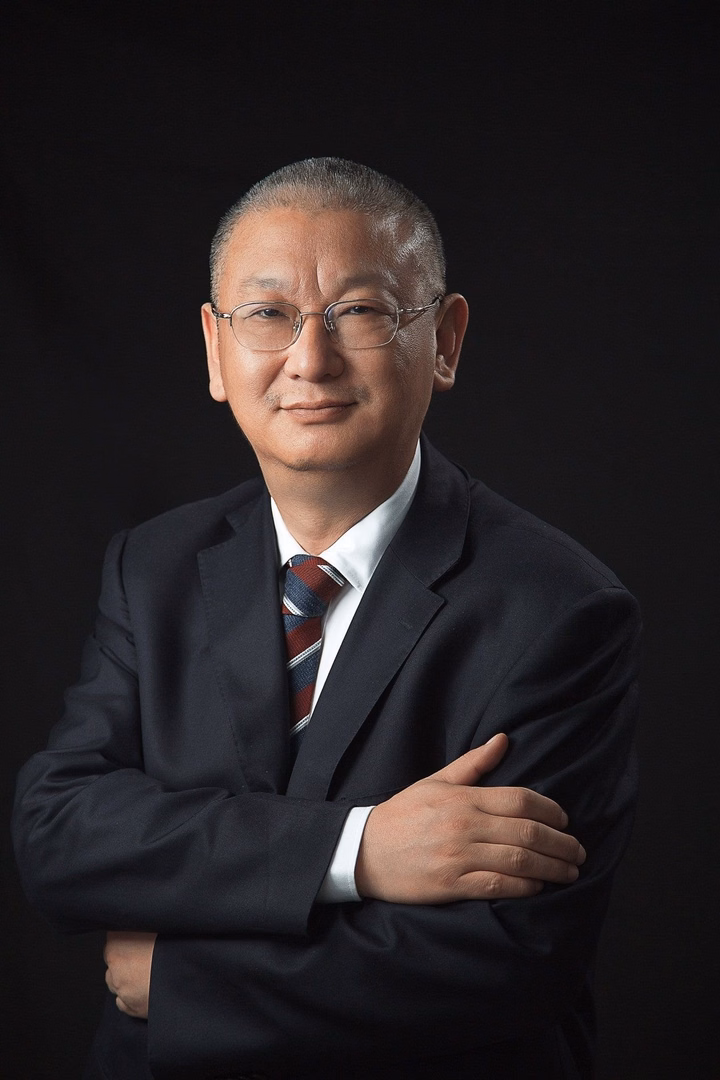 LONGi President Li Zhenguo in a suit and tie, with arms crossed, against a black background.