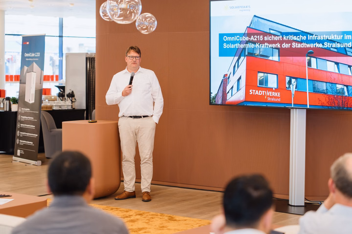 Man speaking in front of a screen showing the Stadtwerke Stralsund building.