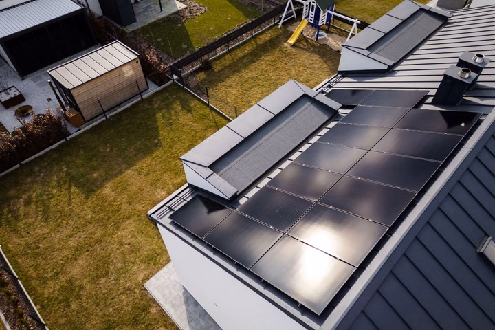 Black solar panels installed on a modern dark roof of a family home.