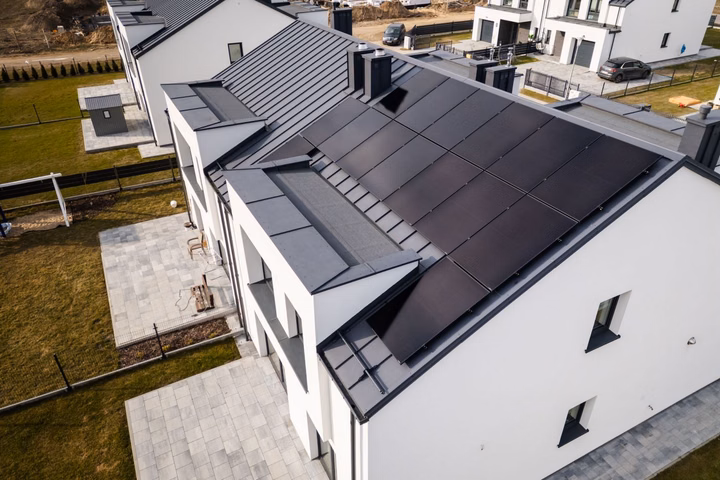 Modern white house with dark solar panels on the roof in Poland.
