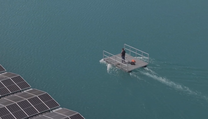 Technician on a boat inspecting floating solar panels at the Waldmattensee solar farm.
