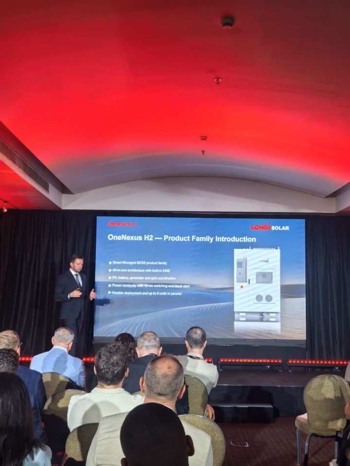 A presenter introducing the LONGi OneNexus H2 microgrid energy storage system at a corporate event.