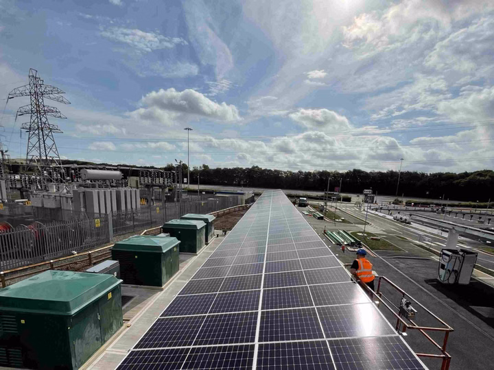 Worker installing LONGi solar panels on the roof of the NEC Gigahub EV charging station in Birmingham.